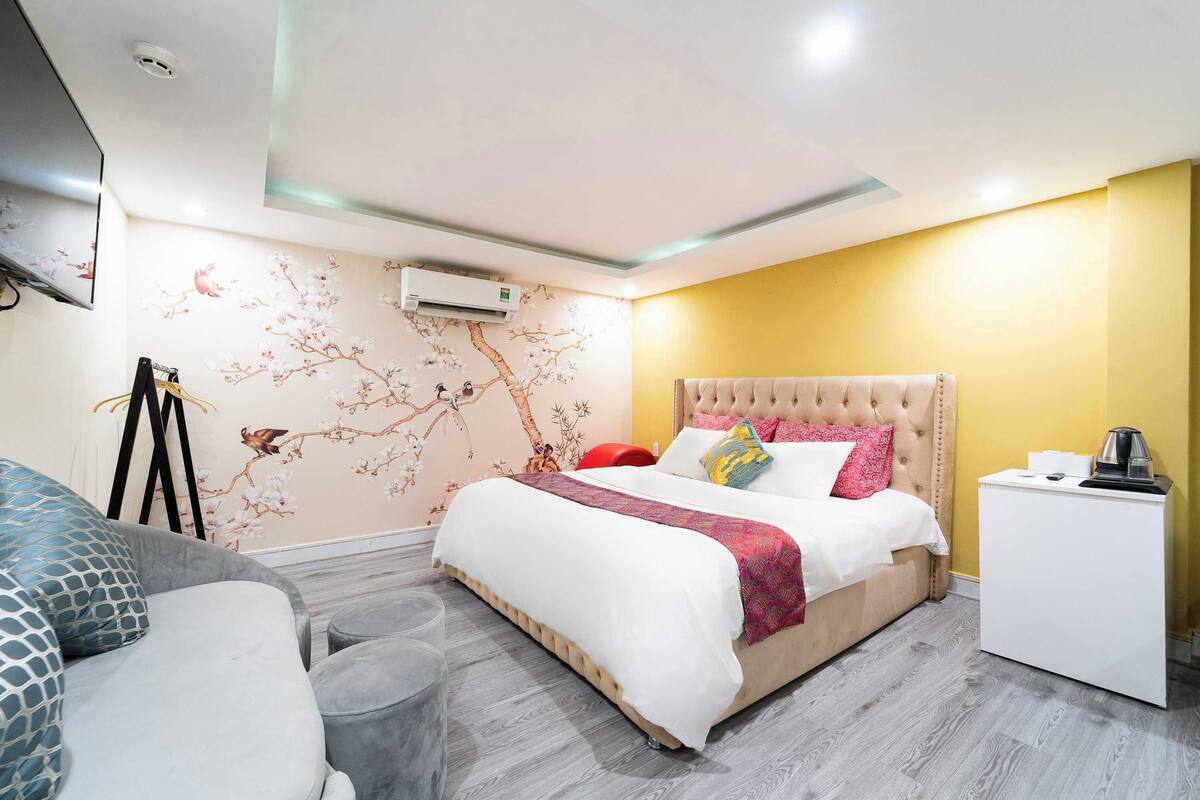 A modern bedroom with a bed, bedside table, and a small white cabinet.