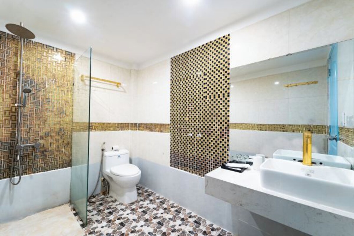 A bathroom with a glass-enclosed shower, a toilet, and a sink with a mirror.