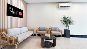 A modern lounge area with wicker sofas, a round coffee table, and a potted plant. - Collection O Joy Inn - Near T3 Terminal (Ho Chi Minh City)