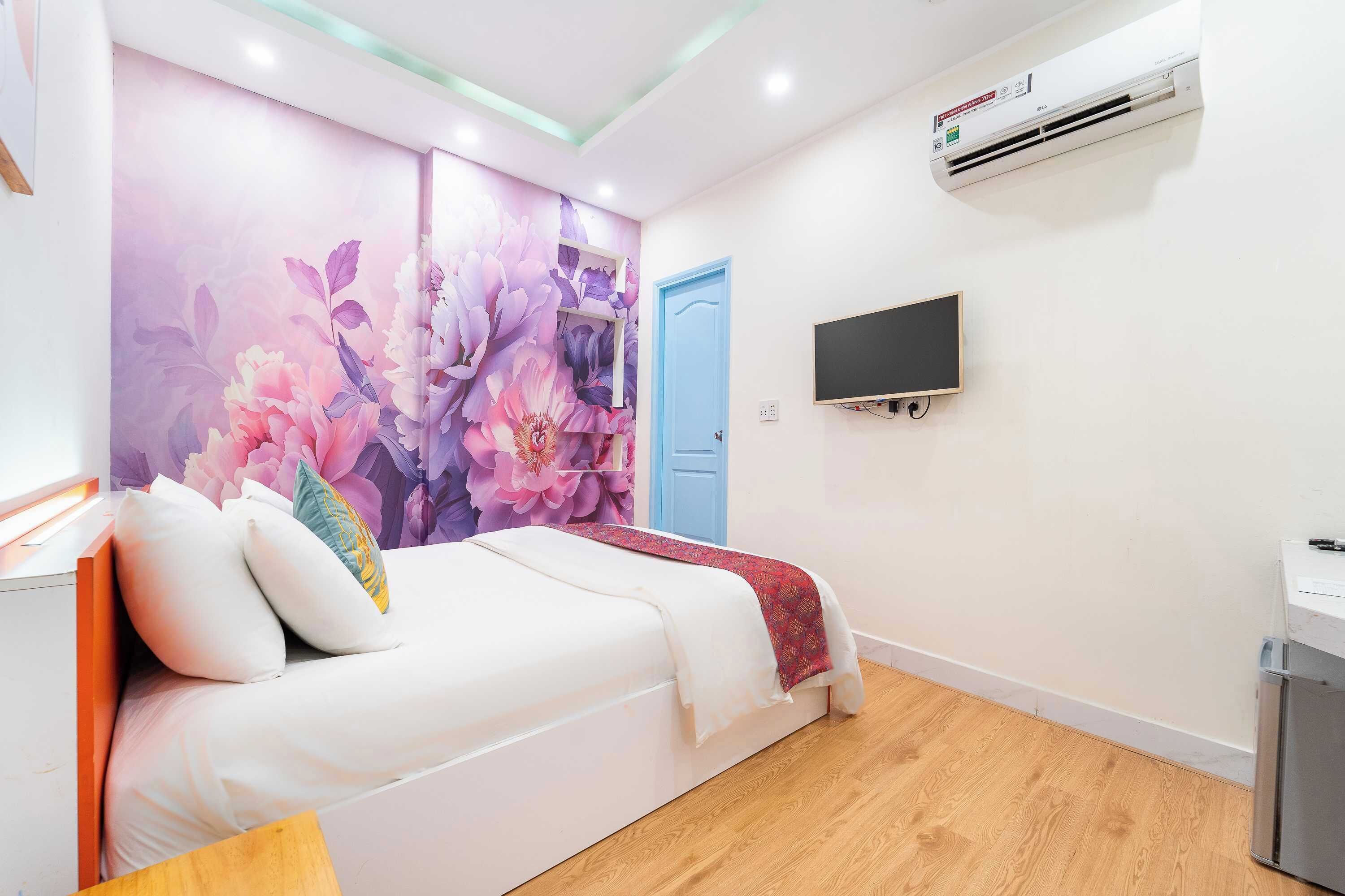 A bedroom with a bed, a wall-mounted TV, an air conditioner, and a door.
