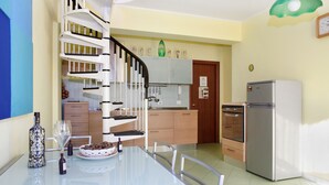 A modern kitchen with a spiral staircase, a dining table with chairs, and a refrigerator. - Adriana Sicily House  Etna & Sea Tripiti with parking check in 24H (Acireale)