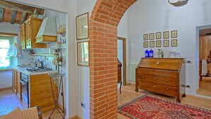 Une cuisine avec des meubles de rangement en bois, une cuisinière à gaz et un luminaire suspendu.