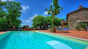 Une piscine aux eaux cristallines, avec des chaises longues et un bâtiment en pierre en arrière-plan.