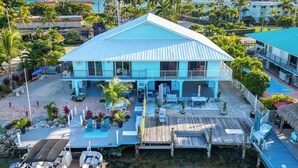 A large house with a pool, outdoor seating, and a boat docked at the water's edge.