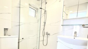 A modern bathroom with a glass-enclosed shower, a toilet, and a vanity with a mirror. - Domus Dulcis Domus (Limenas Chersonisou)