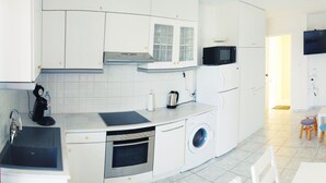 A compact kitchen with a microwave, oven, sink, and a washing machine. - Domus Dulcis Domus (Limenas Chersonisou)