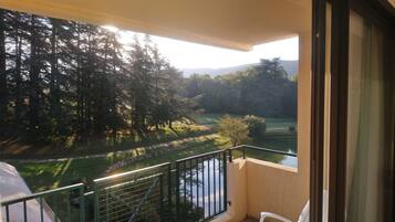 A balcony with a view of a lake, trees, and a distant mountain range.