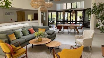 A modern living room with a sofa, chairs, a coffee table, and a dining area with a table and chairs.