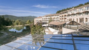 Um hotel com várias varandas, piscina e vista para um lago e montanhas.