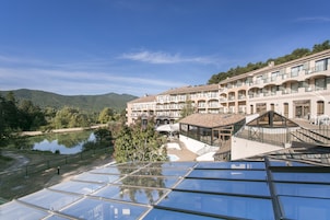 Un hotel con varios balcones, piscina y vistas a un lago y montañas.