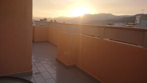 Een balkon met uitzicht op de ondergaande zon boven de bergen.
