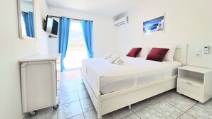 Een hotelkamer met een bed, nachtkastje, bureau, stoel, televisie en raam met gordijnen.