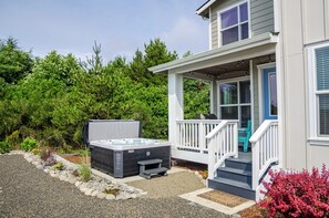 A house with a covered porch, a hot tub, and a staircase leading to the entrance.