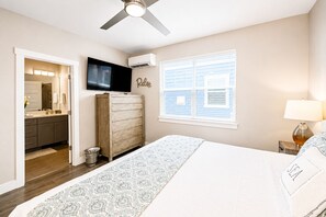 Ein Schlafzimmer mit einem Bett, einem Fernseher, einem Kleiderschrank, einem Fenster mit Jalousien und einem Deckenventilator.