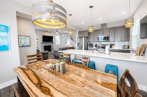 Eine moderne Küche mit Kochinsel, Edelstahlgeräten und einem Essbereich mit Holztisch und Stühlen.
