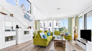 A modern living room with a sofa, coffee table, and TV. - Villa Seemööv - waterfront, terrace, whirlpool, sauna, fireplace, e-charging (Olpenitz)