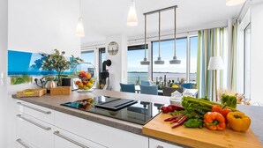 A modern kitchen with a large island, stainless steel appliances, and a view of the sea. - Villa Seemööv - waterfront, terrace, whirlpool, sauna, fireplace, e-charging (Olpenitz)