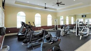 Ein Fitnessstudio mit Laufbändern, Kraftgeräten und einer Spiegelwand.