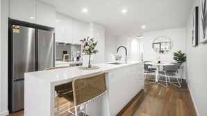 Una cocina moderna con gabinetes blancos, electrodomésticos de acero inoxidable y una isla central con asientos.