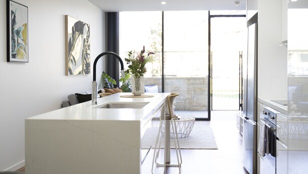 Cocina moderna con una isla central, electrodomésticos de acero inoxidable y un amplio ventanal que proporciona luz natural.