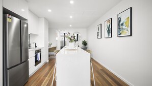 Una cocina moderna con armarios blancos, electrodomésticos de acero inoxidable y una isla central.