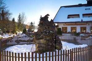 A rustic stone structure surrounded by a wooden fence, with a building labeled 'Gasthof' in the background.