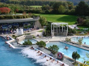 A swimming pool area with multiple pools, a water slide, and a covered seating area. - Einzelzimmer - Stahlecker Hof (Lichtenstein)