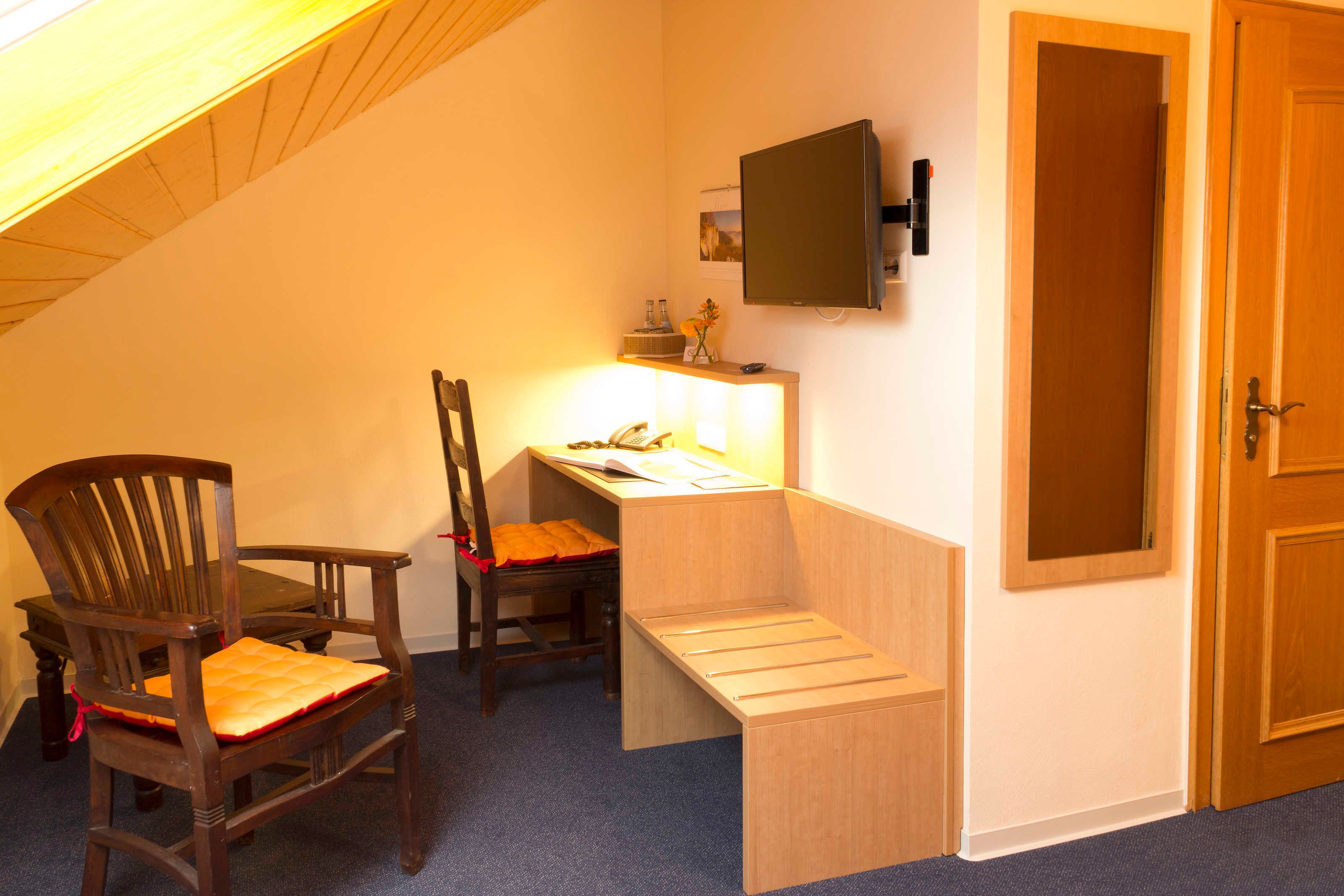 Ein Zimmer mit Schreibtisch, zwei Stühlen, einem Fernseher und einer Tür.