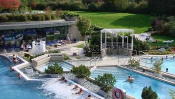Area piscina con diverse piscine, uno scivolo acquatico e una zona relax coperta.