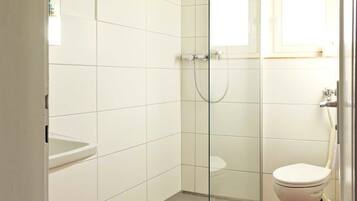 Ein modernes Badezimmer mit einer gläsernen Dusche, einer weißen Toilette und einem roten Teppich.