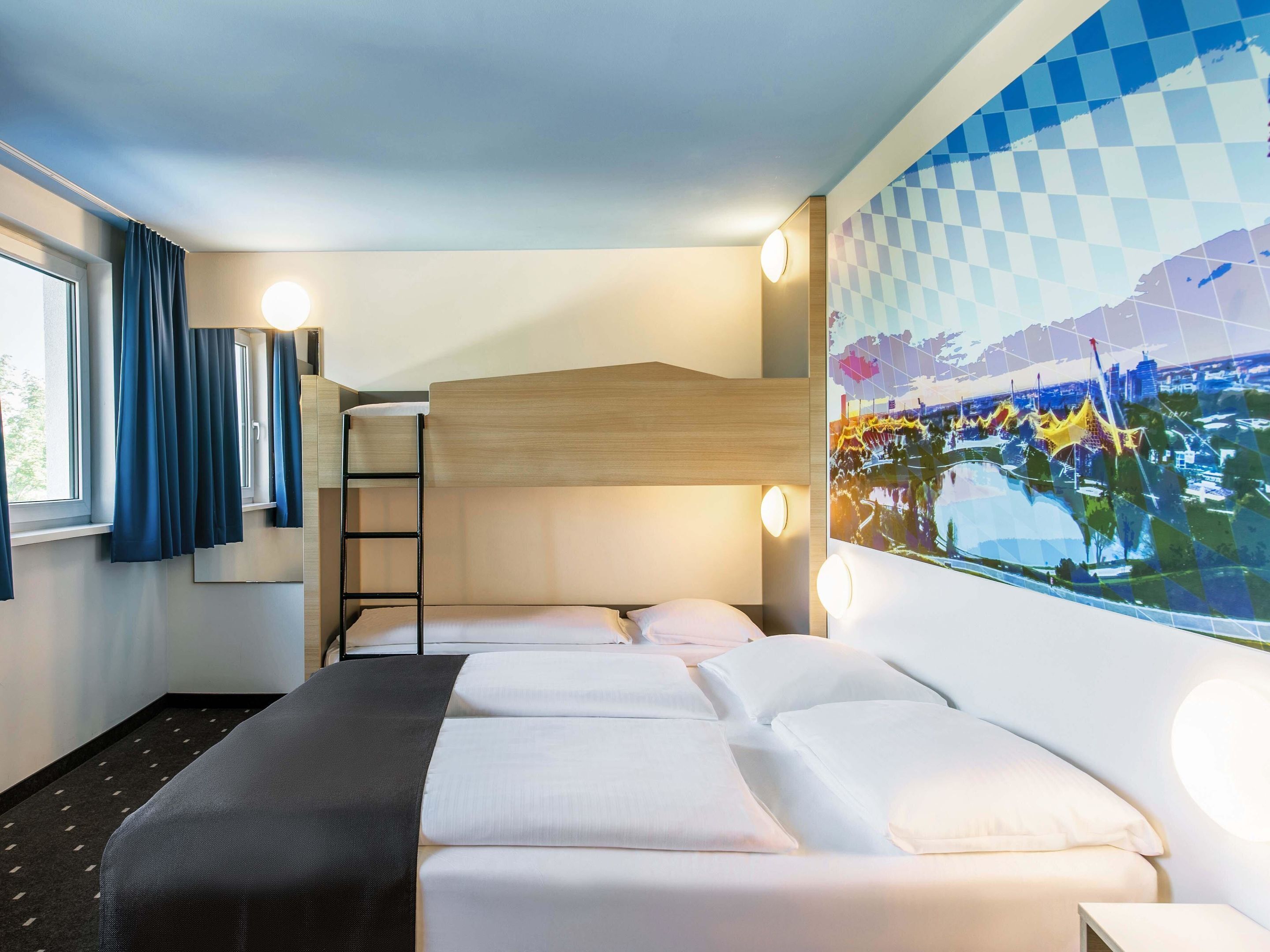 A hotel room with a bunk bed, a desk, a window with curtains, and a wall-mounted artwork.