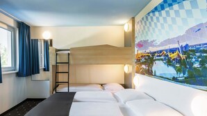 Habitación de hotel con literas, un escritorio, una ventana con cortinas y una obra de arte en la pared.