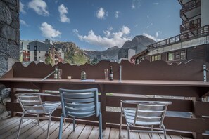 A wooden deck with metal chairs and a bar area overlooking a mountainous landscape. - Curling Hôtel & Bar (Tignes)