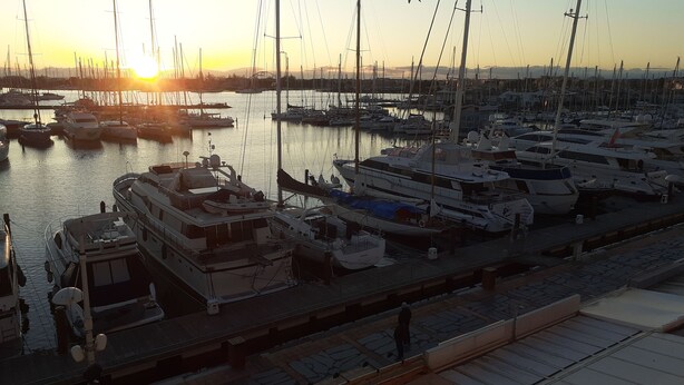 Un puerto deportivo con varios barcos amarrados al muelle al atardecer.