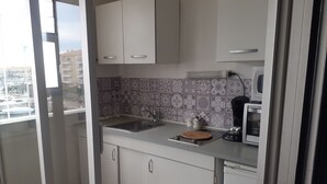 Una cocina moderna con armarios blancos, un lavamanos de acero inoxidable y un protector contra salpicaduras estampado.