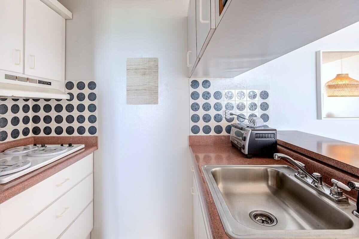 A kitchen with white cabinets, a stainless steel sink, and a toaster on the counter.