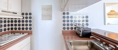 A kitchen with white cabinets, a stainless steel sink, and a toaster on the counter.