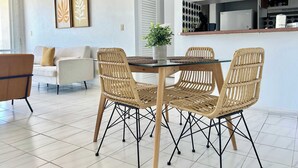 Un salon moderne avec un coin repas comprenant des chaises en osier et une table en verre.