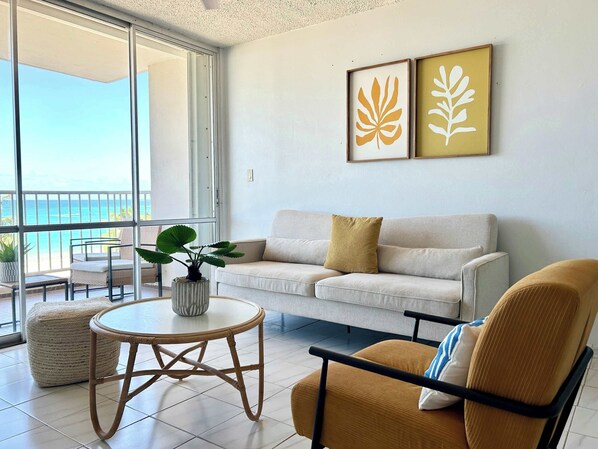 Un salon moderne avec un balcon, un canapé blanc, une table ronde et un fauteuil.