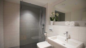 Un baño moderno con ducha acristalada, lavamanos blanco y retrete.