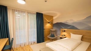 Habitación de hotel con cama, escritorio, silla y lámpara de pared.