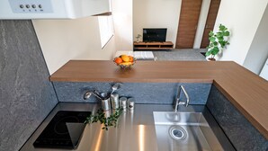 Una cocina moderna con estufa integrada, un lavamanos y una encimera con fruteros.