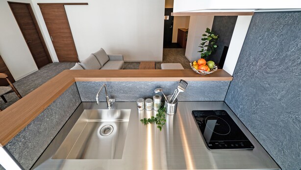 Una cocina moderna con un lavamanos de acero inoxidable, una placa de inducción y una encimera con utensilios de cocina.