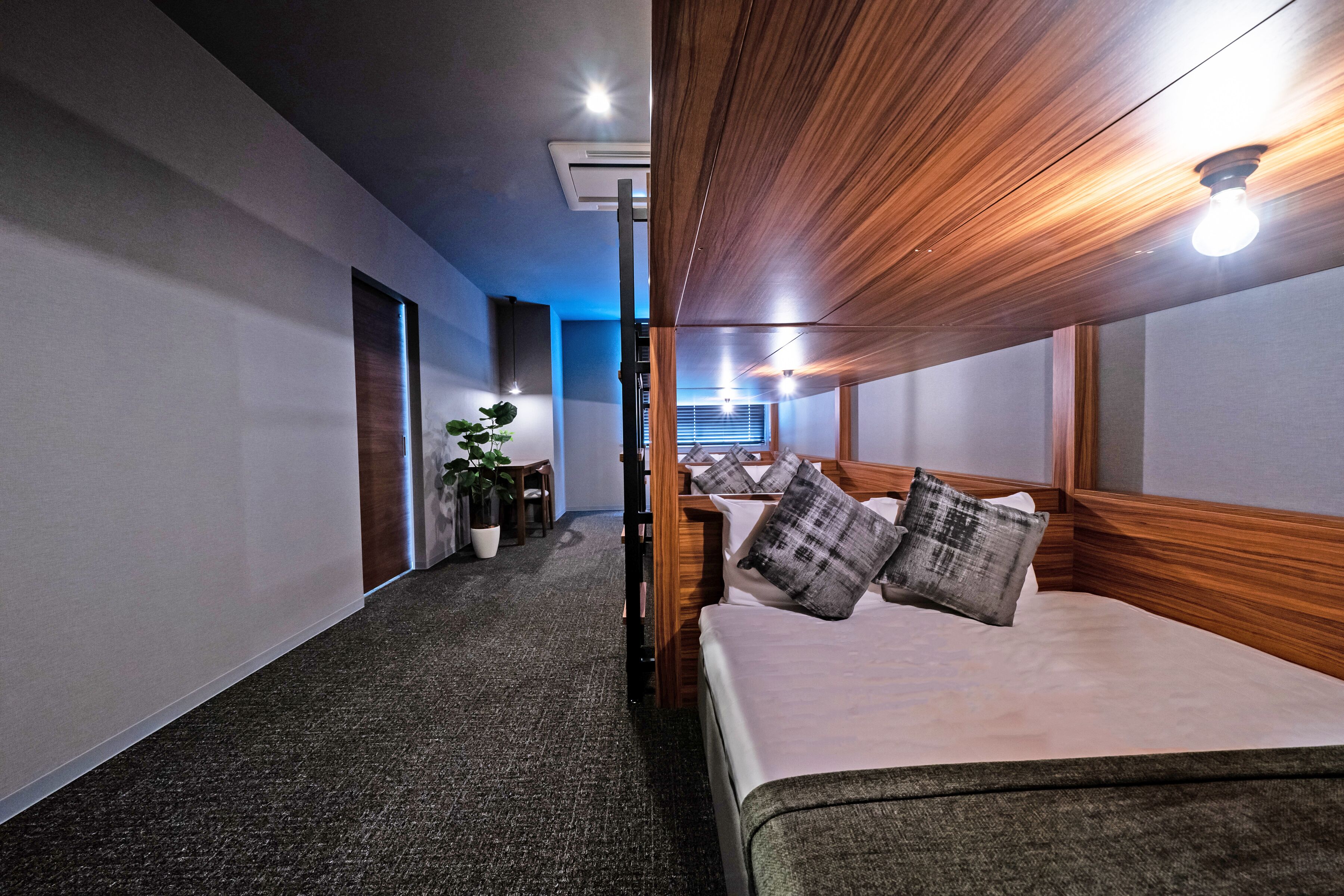 A hotel room with a large bed, a desk, a chair, and a potted plant.
