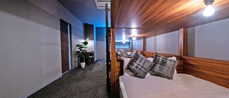 A hotel room with a large bed, a desk, a chair, and a potted plant.