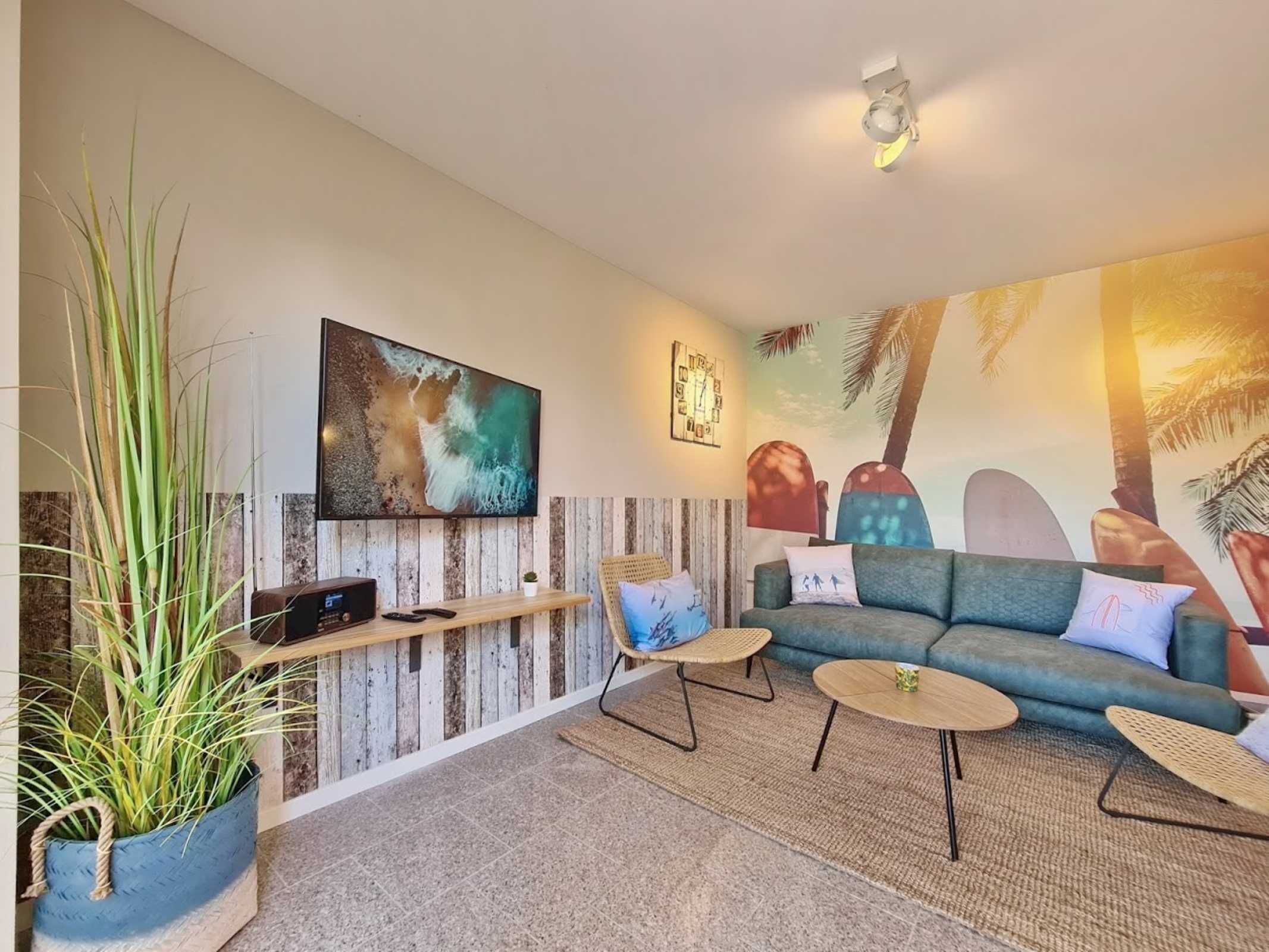 A modern living room with a large flat-screen TV, a sofa, two small round tables, and a potted plant.