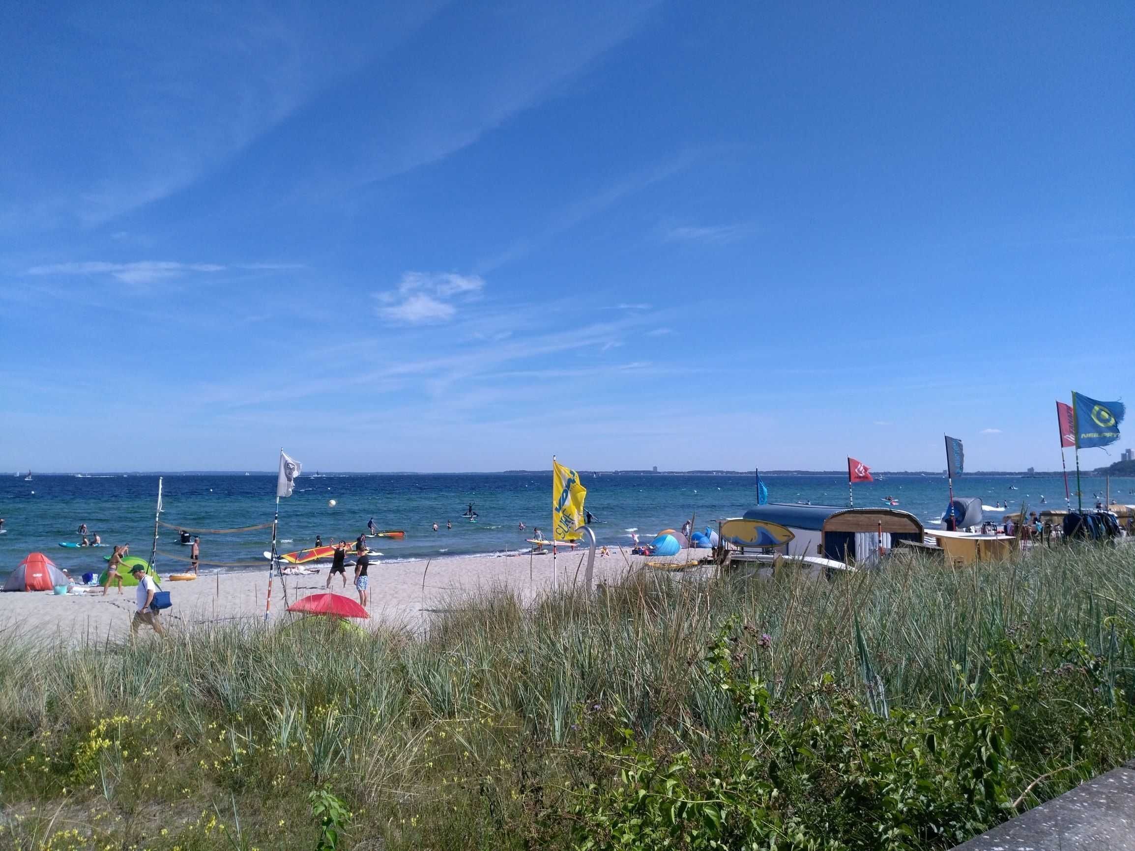 A beach with tents, flags, and people.