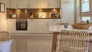 A modern kitchen with white cabinets, a built-in oven, and a coffee maker on the countertop. - Malibu SA 57a - Malibu, 3 rooms, 65m², terrace, sauna (Scharbeutz)