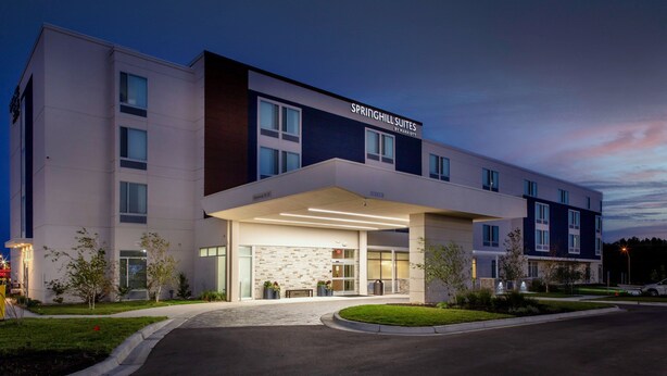 Un hotel moderno con tejado plano, ventanas amplias y una entrada bien iluminada.