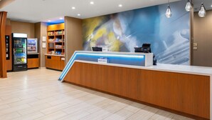 Zona de recepción de un hotel con un mostrador de madera, una máquina expendedora y un bar de aperitivos.